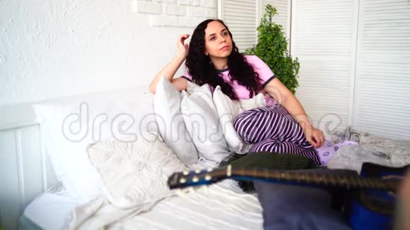可爱的一对吉他坐在床上男人在床上为你女朋友演奏蓝色的吉他视频的预览图