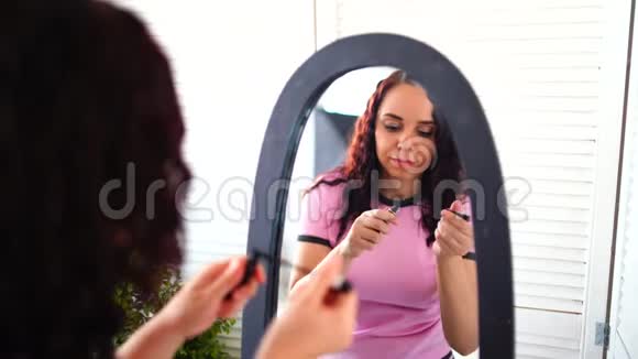 年轻漂亮的女人穿着睡衣在家里照镜子画着睫毛膏与迷人的女性亲密接触视频的预览图