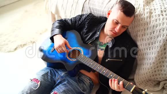 一个胸前有纹身的年轻人在卧室里弹吉他希普斯特学会弹吉他特写镜头视频的预览图