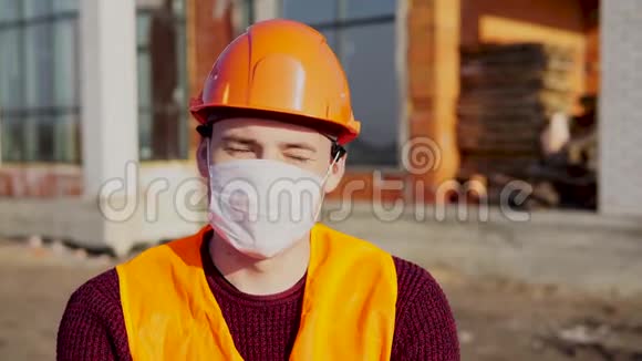 在建房屋背景上戴医用口罩工作服的男建筑工人画像视频的预览图