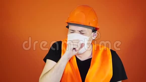 男施工工穿着工作服和医用口罩在橙色背景下咳嗽感染威胁的概念视频的预览图