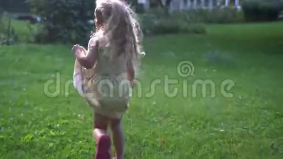 一个金发碧眼的小女孩在夏日花园的草地上奔跑视频的预览图