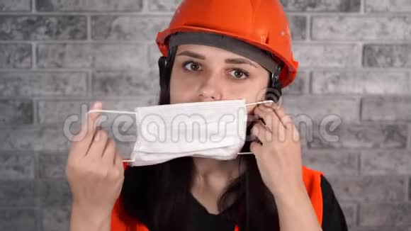 穿工作服的女建筑工人在灰砖墙背景上戴医用口罩视频的预览图