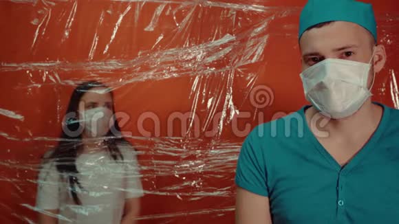 年轻女子戴着医用口罩被迫与冠状病毒隔离前景中戴医用面罩的男医生把他隔离了视频的预览图