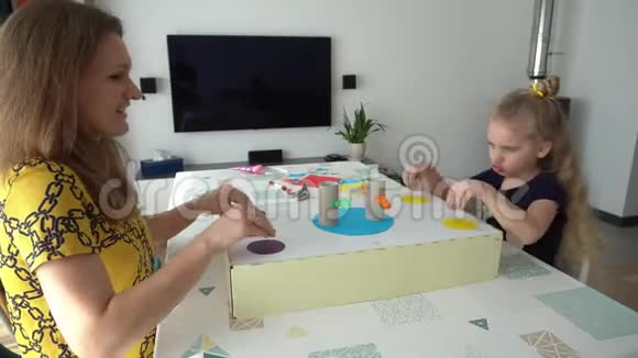 妈妈和金发孩子坐在桌旁玩游戏视频的预览图