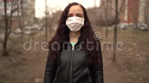 站在街上的年轻女子戴着医用面具的肖像成年女性用面具遮住她的脸视频的预览图