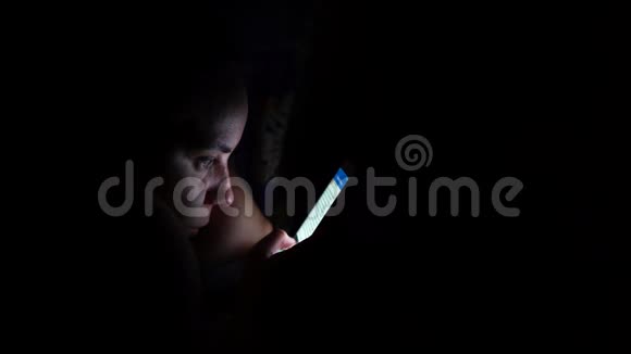 在黑暗中使用手机的成年女性带智能手机的年轻女性在家中卧室视频的预览图