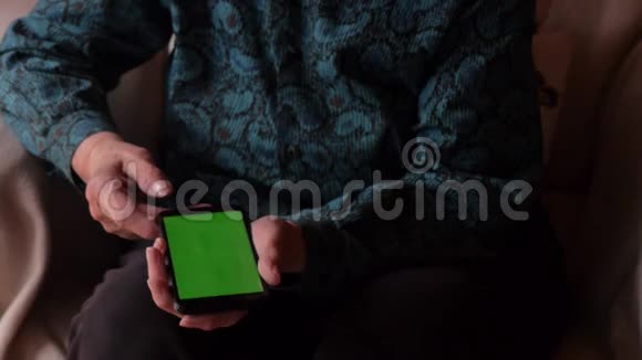 握着智能手机的老年人的旧手试图找出这个小玩意绿色屏幕冠状病毒大流行视频的预览图