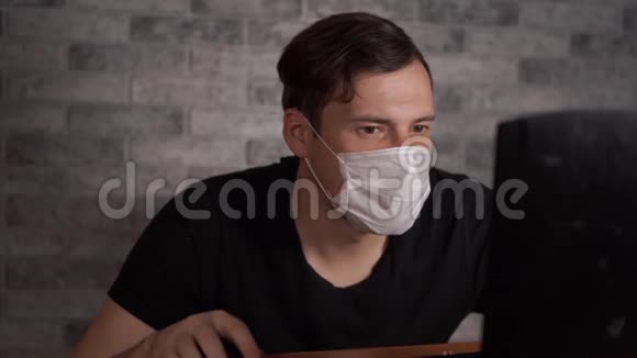一个戴着医用面具的人用笔记本电脑从互联网上得知冠状病毒的消息男性关心他的视频的预览图