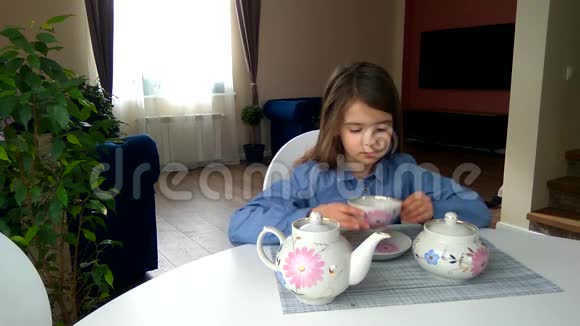 女孩坐在桌子旁从杯子里倒茶喝茶视频的预览图