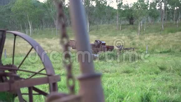 在绿草如茵的围场上的旧生锈的农机具向左滑动柔和的灯光视频的预览图