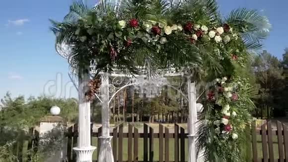 美丽的婚礼拱门装饰着鲜花和棕榈叶在风中发展视频的预览图