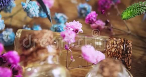 香水装在玻璃瓶中木背景上的新鲜花朵之间有软木帽视频的预览图