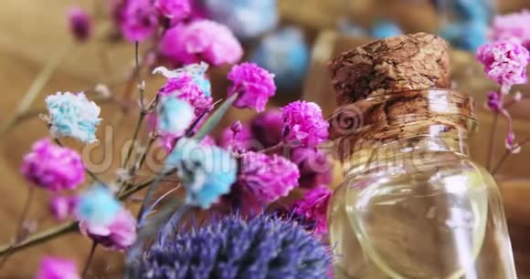 玻璃瓶中的香水木背景上的花之间有软木帽视频的预览图