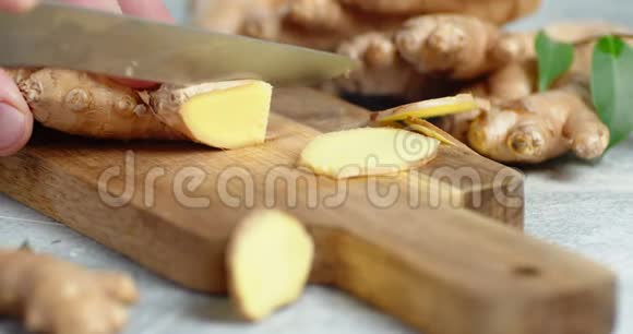 男人手把新鲜的姜切成切片放在木切板上视频的预览图