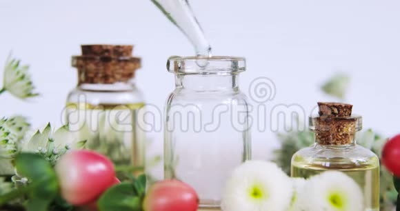 香水在花间的玻璃瓶中制造香气扑鼻的精油视频的预览图