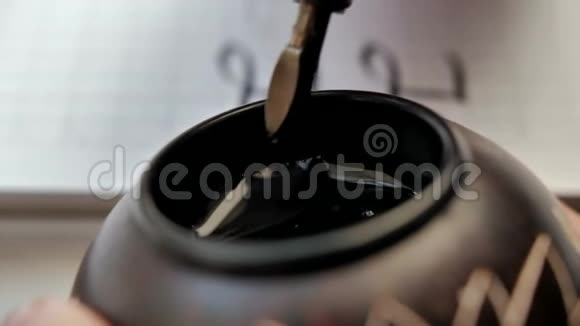 木笔尖放在黑色墨水池里的特写镜头视频的预览图