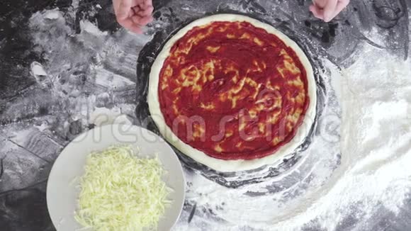 男人的手把奶酪撒在面团上用番茄酱做披萨视频的预览图