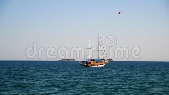 乘船和游艇在海上航行的游客一个人带着降落伞在船后飞翔滑翔伞视频的预览图