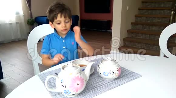 小男孩坐在桌子旁喝杯杯茶视频的预览图