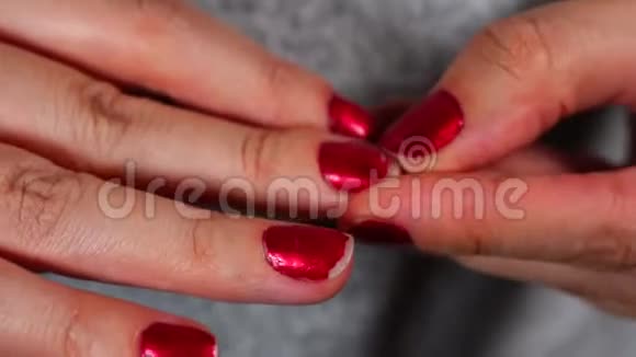 紧张的女人挑着她的红色指甲紧紧抓住女人的手她的指甲女性用红色指甲油视频的预览图
