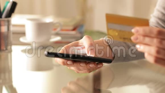女人用信用卡和电话在线购买视频的预览图