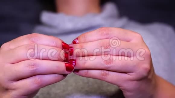紧张的女人挑着她的红色指甲紧紧抓住女人的手她的指甲女性用红色指甲油视频的预览图