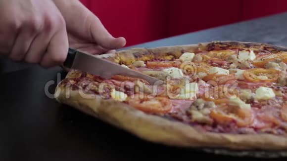 手在黑桌上用肉和西红柿切焦的披萨视频的预览图