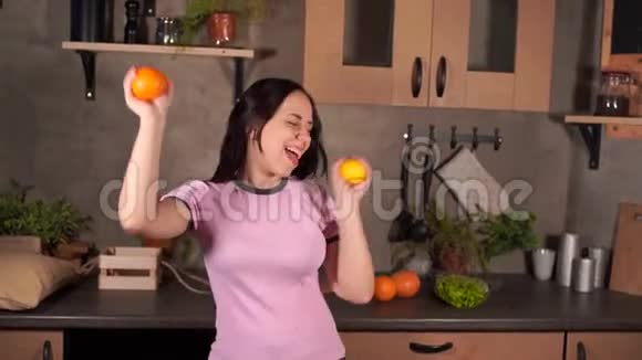 穿着睡衣的漂亮年轻女人手里拿着橘子跳舞一幅迷人的女性嬉笑的肖像视频的预览图
