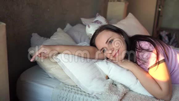 早上穿着睡衣躺在床上抱着枕头的年轻漂亮女人的肖像成人女士休息特写视频的预览图