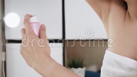 女孩用除臭剂年轻漂亮的女人穿着白色毛巾在浴室里左手在右边喷洒除臭剂视频的预览图