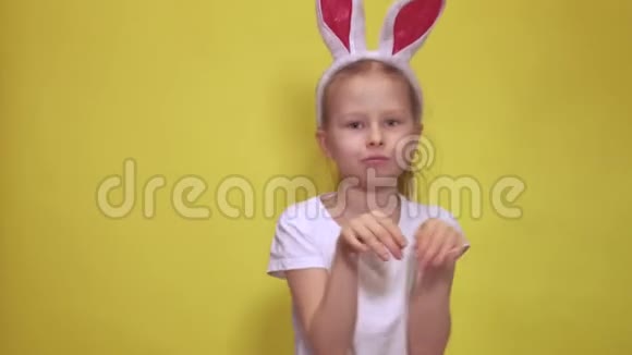 可爱的小女孩长着小兔子的耳朵看着摄像机一边跳着一边假装在复活节庆祝活动中是兔子视频的预览图