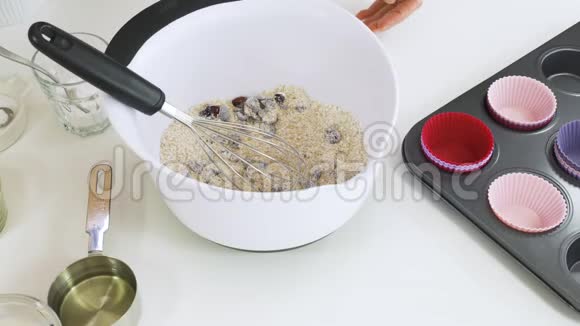 含干蔓越莓配方的布兰松饼将酪乳和植物油与一些干原料混合在碗中视频的预览图