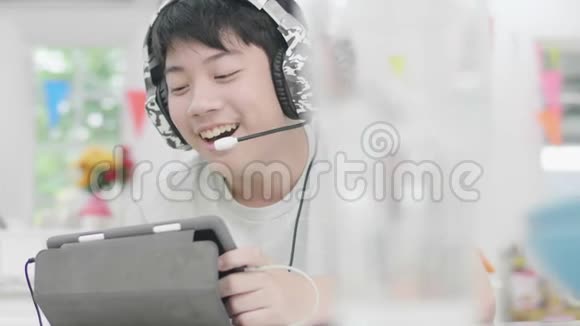 亚洲男孩用平板电脑和朋友玩网络游戏视频的预览图