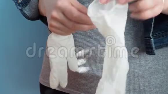 一个穿着日常服装的女孩戴着乳胶白色手套以防止细菌和病毒视频的预览图