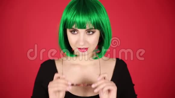 戴着绿色假发和粉色眼镜的漂亮女孩扮鬼脸到处都是傻瓜表达着不同的情感视频的预览图