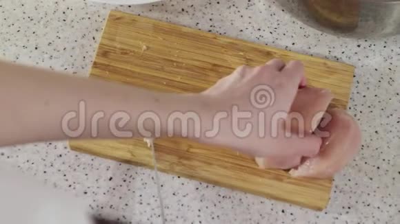 女人把鸡胸肉放在木切割板上视频的预览图