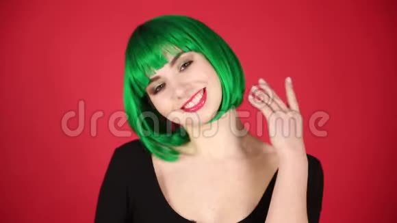 美丽的女孩戴着绿色假发做着鬼脸到处都是傻瓜表达着不同的情感视频视频的预览图