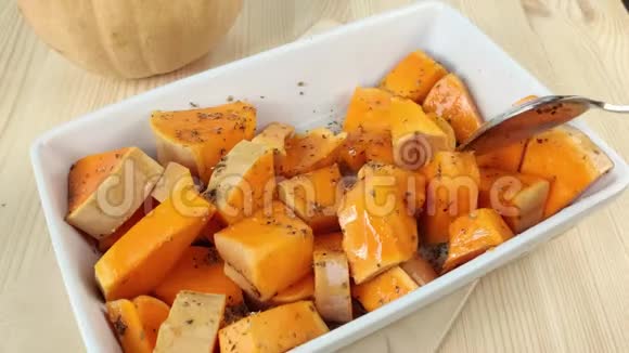 用油切南瓜和干香料用勺子搅拌用白色长方形盘子煮橘子烤南瓜健康视频的预览图