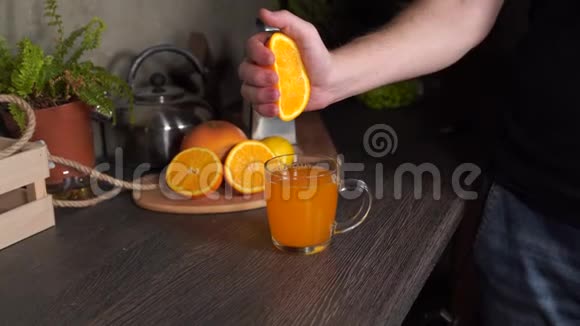 一个男人在厨房里挤压一个橘子得到新鲜的橙汁特写视频的预览图