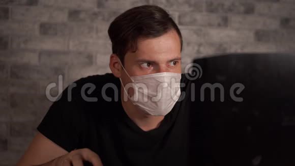 一个戴着医用面具的人用笔记本电脑从互联网上得知冠状病毒的消息男性关心他的视频的预览图