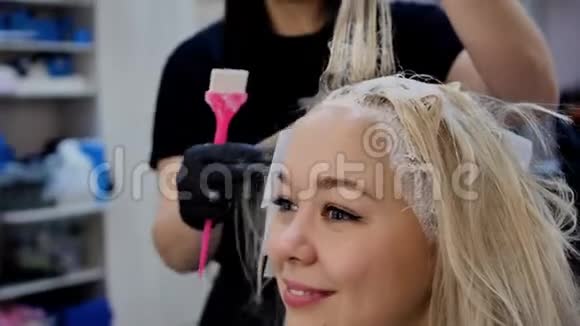 在沙龙里染发年轻漂亮的金发碧眼的金发女郎在理发店染发视频的预览图