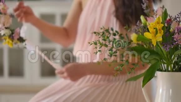一位美丽的亚洲年轻女子的肖像她穿着一件精致的粉红色连衣裙手里拿着春天的花妇女视频的预览图