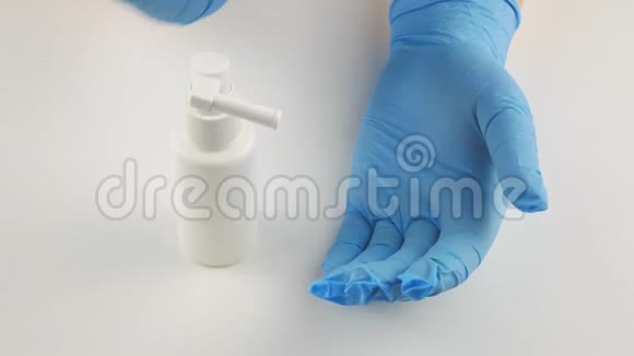 蓝色医用手套上喷洒防腐剂的溅沫在白色背景上视频的预览图