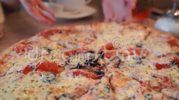 桌上摆着大披萨女人手撕下一块多汁的披萨视频的预览图