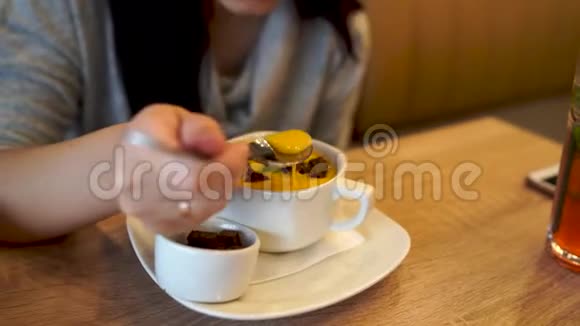在咖啡馆里吃奶酪奶油汤的年轻女人一位成年女性坐在餐厅的餐桌上试着用脆嫩的汤视频的预览图