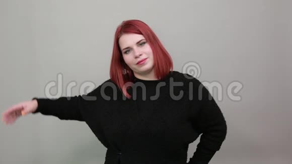 年轻的红头发胖女人穿着黑色毛衣迷人的女人用手摸头发视频的预览图