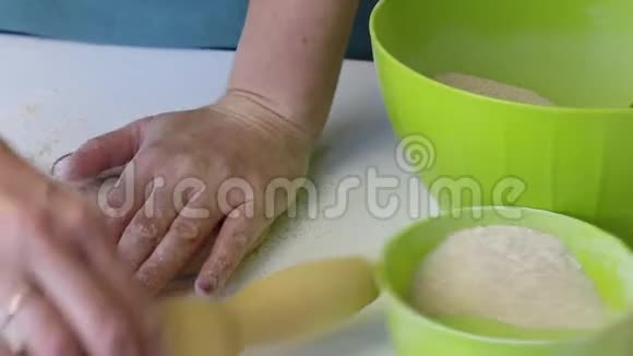 一个女人用手揉一块面团用面粉撒上面团在那之后它用一个滚动销滚出来预科视频的预览图