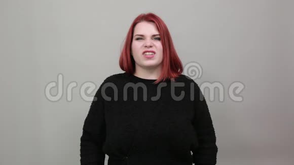 红头发的胖女人穿着黑色毛衣时髦的女人拿着食指挨着脸视频的预览图
