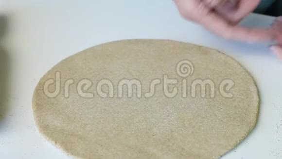 一个女人给她的手一个圆形的蛋糕从一块面团滚出来准备一个新的玉米饼特写视频的预览图